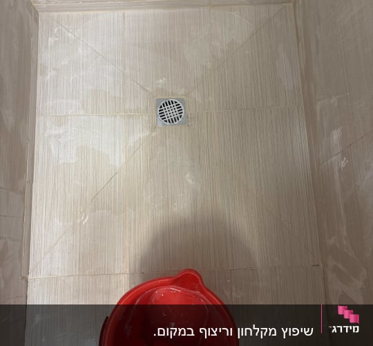 רצפת מקלחת עם דלי אדום ועבודת ריצוף חדשה
